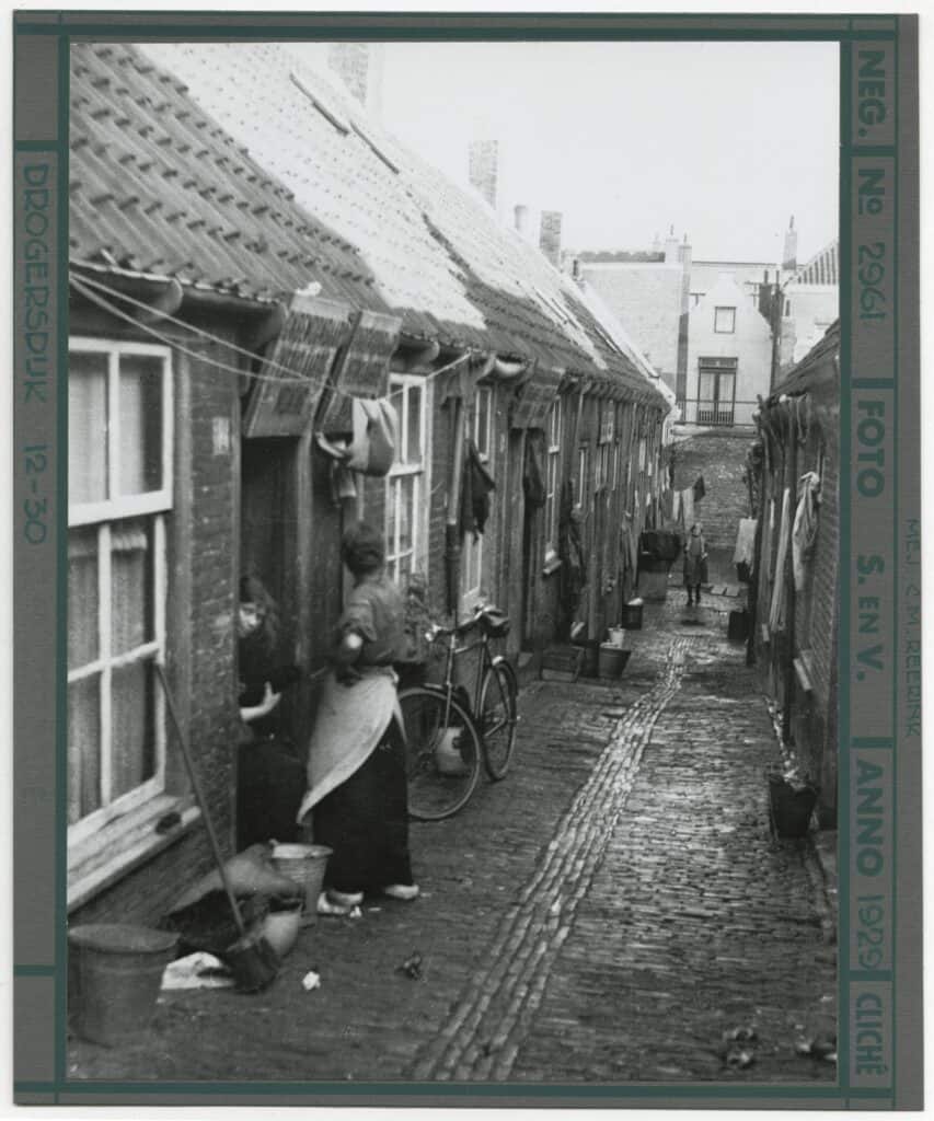 Het kleine Kroonhofje. De huizen op de achtergrond staan aan de Keizerstraat. De woningen zijn onbewoonbaar verklaard en zullen worden gesloopt, Scheveningen, 1929. Bron: Haags Gemeentearchief. 